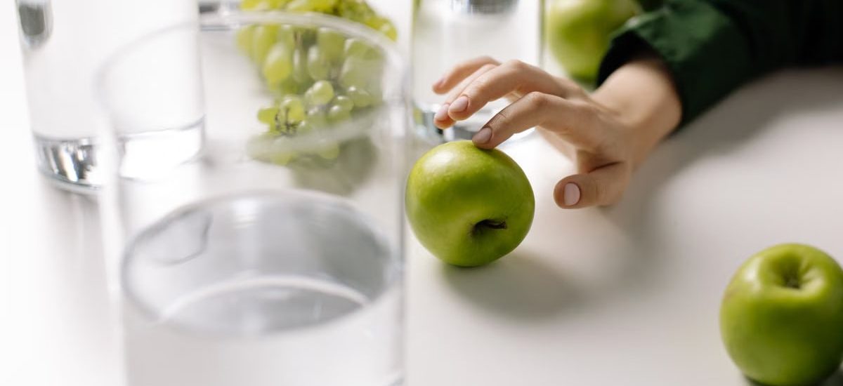 Refreshing image of green apples and grapes with glasses of water on a table, promoting healthy living.