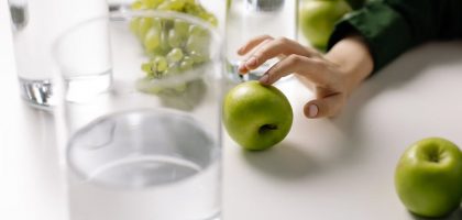 Refreshing image of green apples and grapes with glasses of water on a table, promoting healthy living.