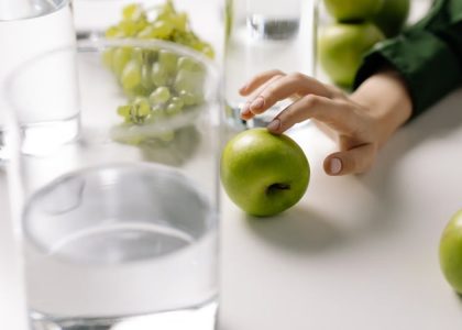 Refreshing image of green apples and grapes with glasses of water on a table, promoting healthy living.